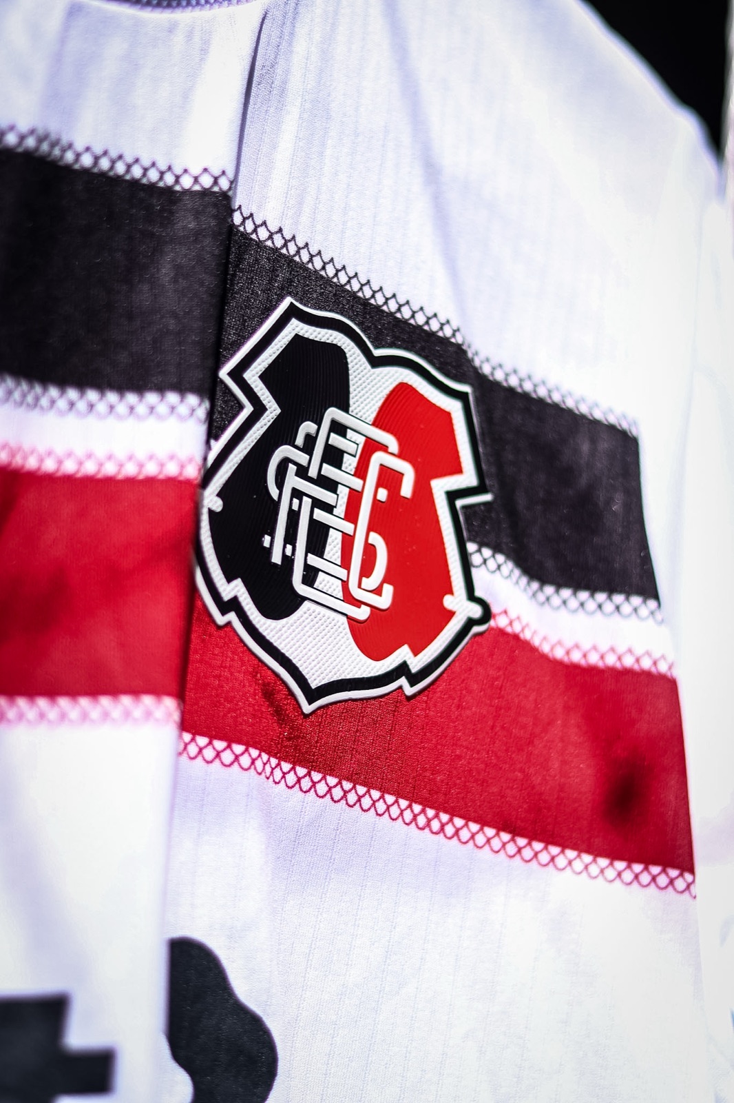 Detalhe do escudo no manto 2026